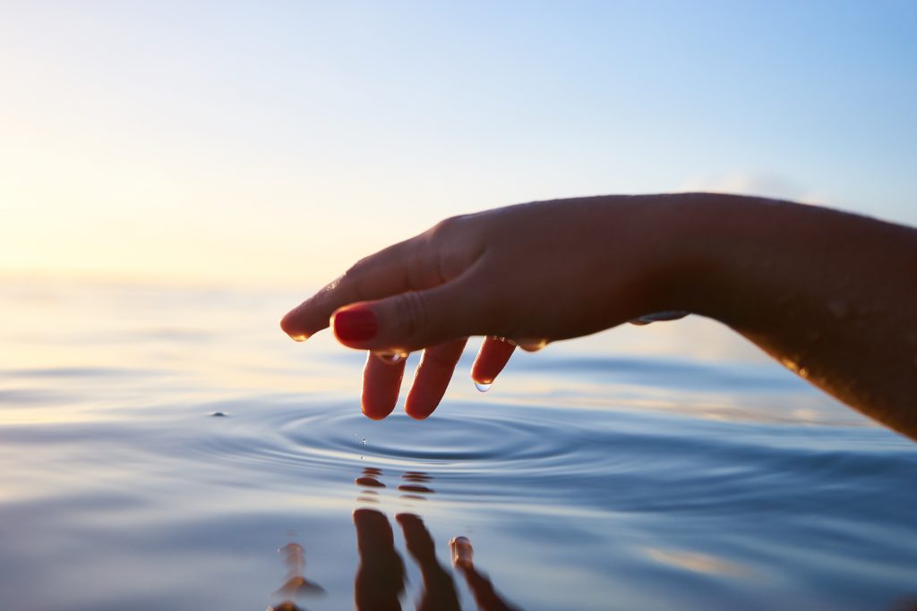 Person about to touch calm water.

Photo by Yoann Boyer on Unsplash